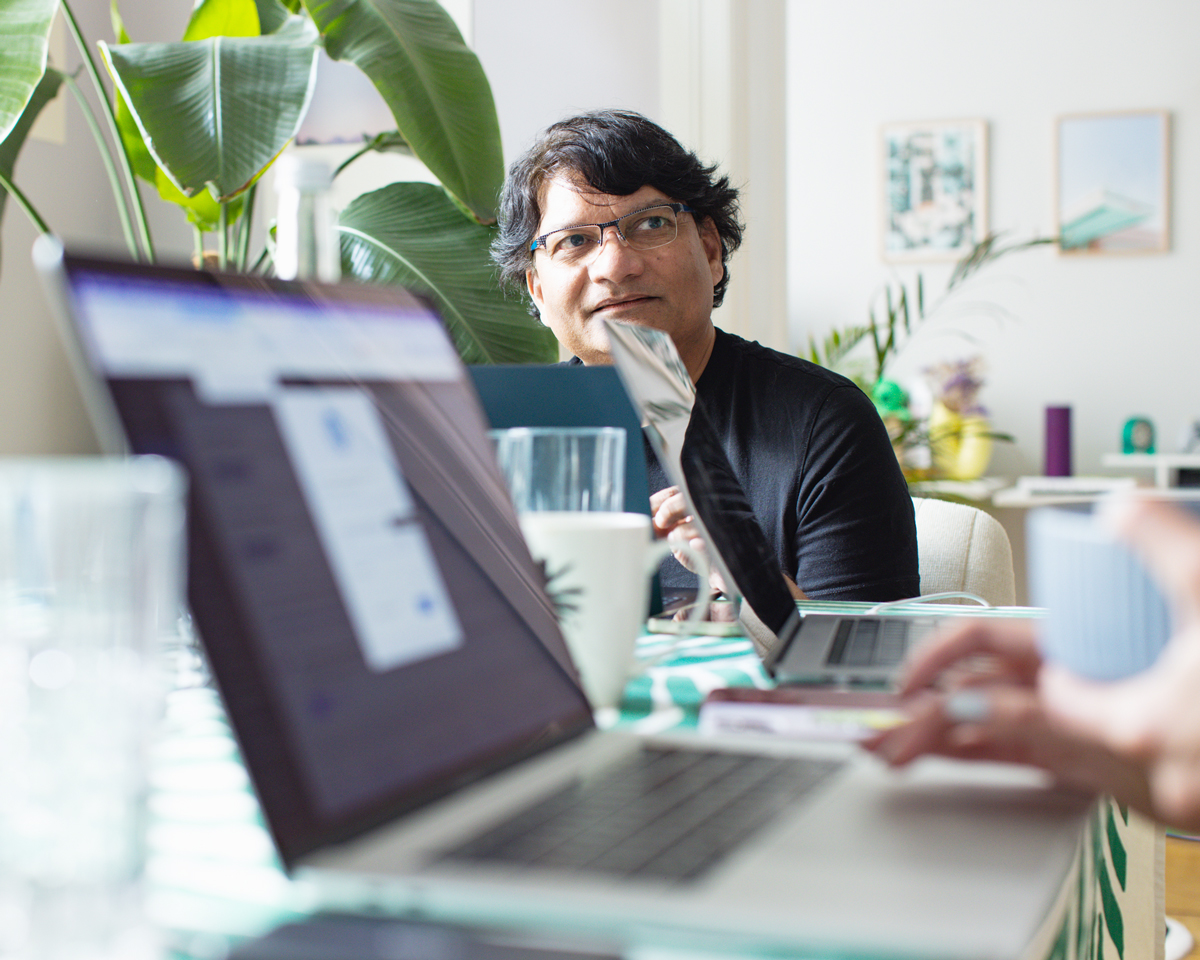 Man working thoughtfully at a laptop surrounded by plants