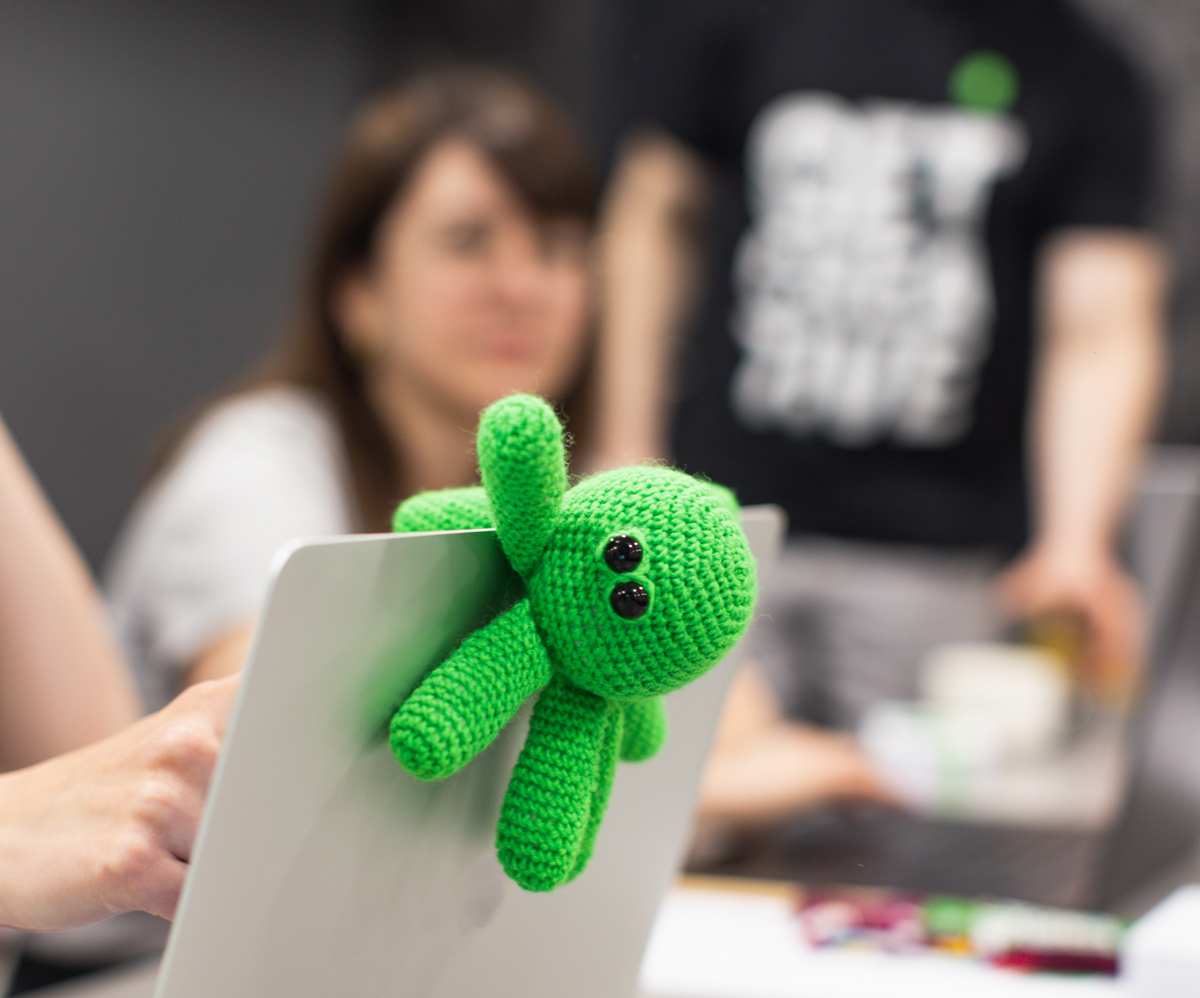 Green crocheted octopus perched on a laptop during a workshop